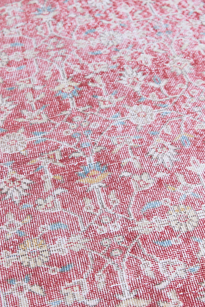 Teresa is a vintage rug handwoven in Turkey approximately 80 years ago. The warm red field and soft blue and beige border are intertwined with an all over flowering vine pattern.