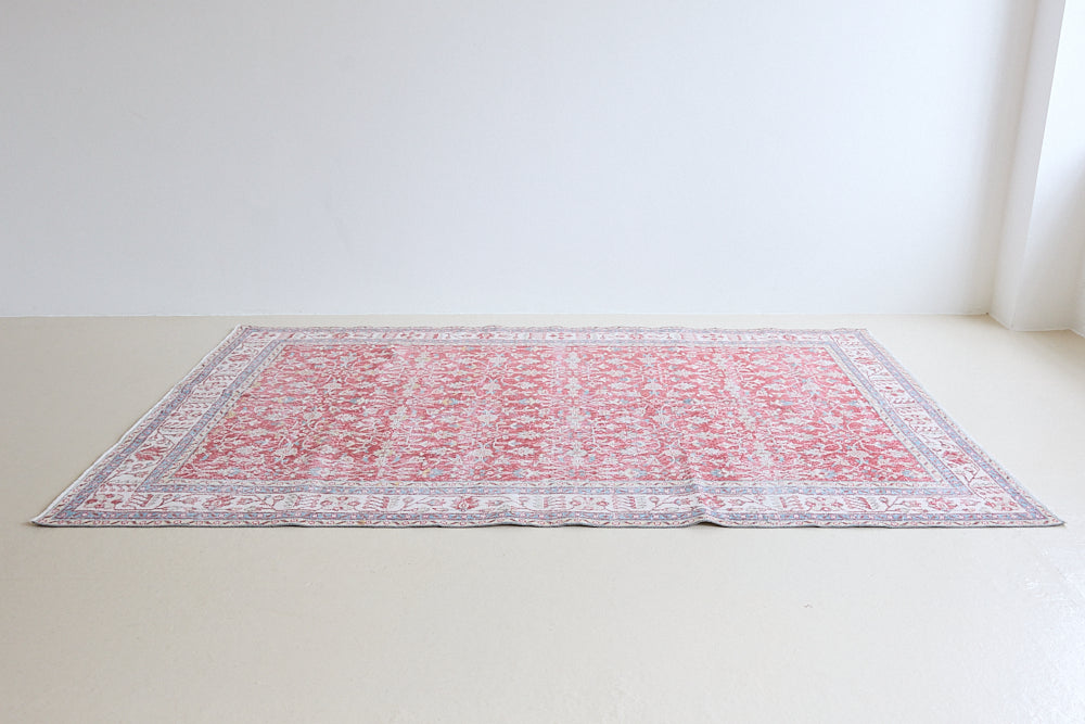 Teresa is a vintage rug handwoven in Turkey approximately 80 years ago. The warm red field and soft blue and beige border are intertwined with an all over flowering vine pattern.