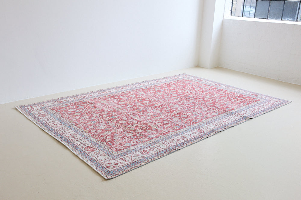 Teresa is a vintage rug handwoven in Turkey approximately 80 years ago. The warm red field and soft blue and beige border are intertwined with an all over flowering vine pattern.
