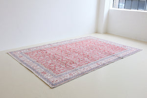 Teresa is a vintage rug handwoven in Turkey approximately 80 years ago. The warm red field and soft blue and beige border are intertwined with an all over flowering vine pattern.