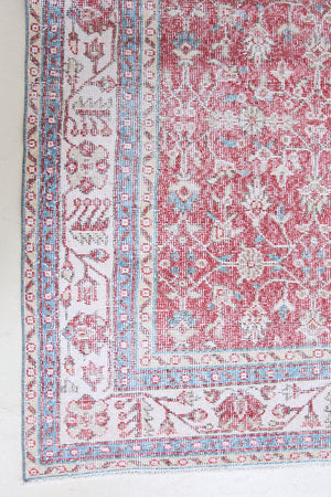 Teresa is a vintage rug handwoven in Turkey approximately 80 years ago. The warm red field and soft blue and beige border are intertwined with an all over flowering vine pattern.