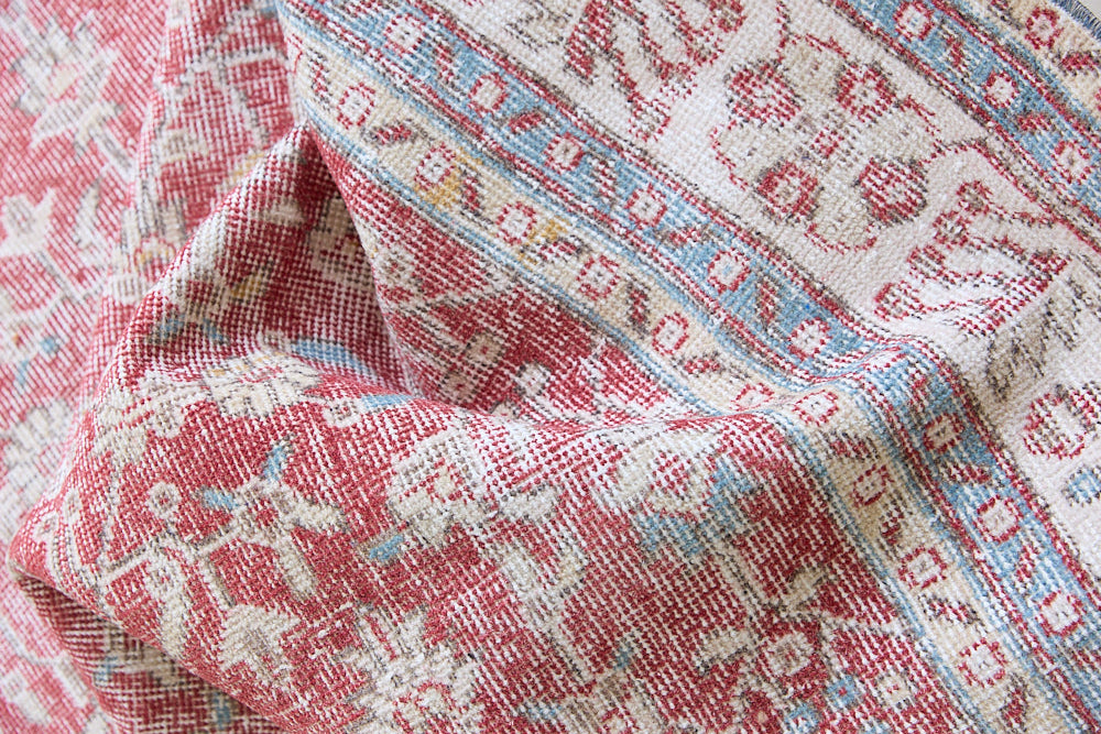 Teresa is a vintage rug handwoven in Turkey approximately 80 years ago. The warm red field and soft blue and beige border are intertwined with an all over flowering vine pattern.