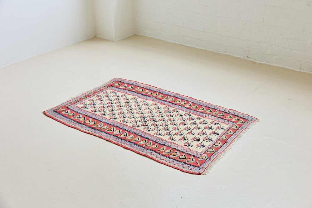Delara is a pretty, geometric Anatolian kilim rug. Hand-woven on village and nomadic looms in vivid, naturally dyed colours, a tradition stretching back thousands of years. Kilims were woven for the practicalities of daily life and used as floor and wall coverings, storage bags, and prayer mats. Delara features a bright red floral motif across a taupe field with a contrasting taupe boarder.