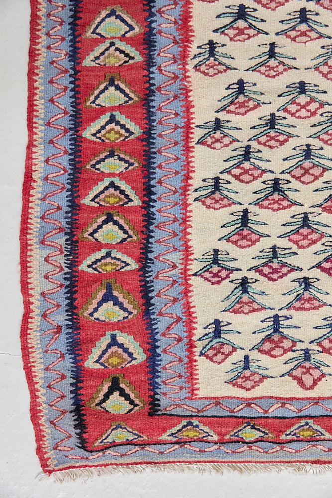 Delara is a pretty, geometric Anatolian kilim rug. Hand-woven on village and nomadic looms in vivid, naturally dyed colours, a tradition stretching back thousands of years. Kilims were woven for the practicalities of daily life and used as floor and wall coverings, storage bags, and prayer mats. Delara features a bright red floral motif across a taupe field with a contrasting taupe boarder.