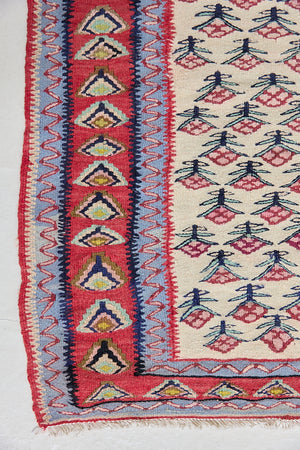 Delara is a pretty, geometric Anatolian kilim rug. Hand-woven on village and nomadic looms in vivid, naturally dyed colours, a tradition stretching back thousands of years. Kilims were woven for the practicalities of daily life and used as floor and wall coverings, storage bags, and prayer mats. Delara features a bright red floral motif across a taupe field with a contrasting taupe boarder.