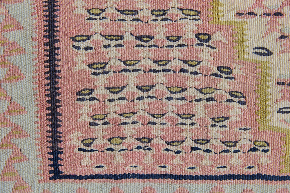An antique Senneh kilim rug. Lale features a delicate pink and taupe central lozenge medallion on a taupe floral field with contrasting boarder.