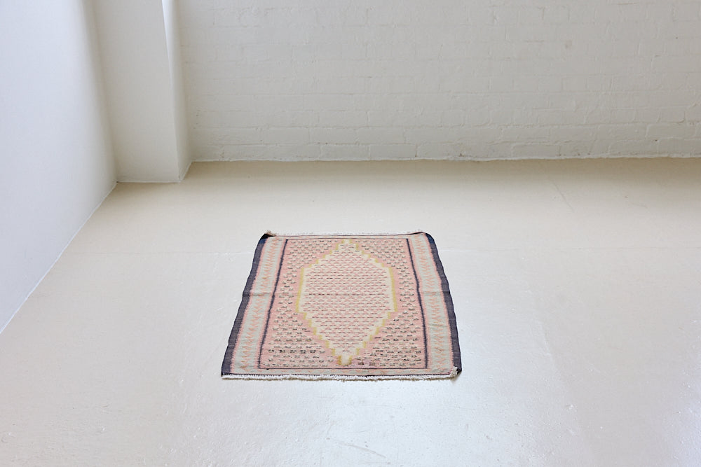 An antique Senneh kilim rug. Lale features a delicate pink and taupe central lozenge medallion on a taupe floral field with contrasting boarder.