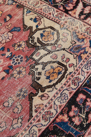 Camille is an antique hand-woven Ushak rug with two central medallions floating on a muted field of rust and taupe, anchored by a striking black floral border.