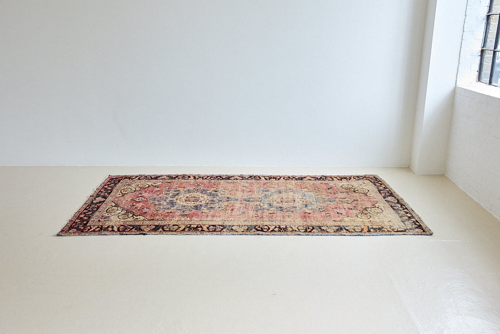 Camille is an antique hand-woven Ushak rug with two central medallions floating on a muted field of rust and taupe, anchored by a striking black floral border.