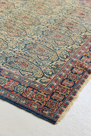 Claudette is a beautiful antique Senneh rug with an intricate design. Senneh rugs are known for their fine and intricate patterns and distinctive weaving technique. Claudette has an intricate botteh pattern and a pleasing colour palette of yellow, muted red and blue.