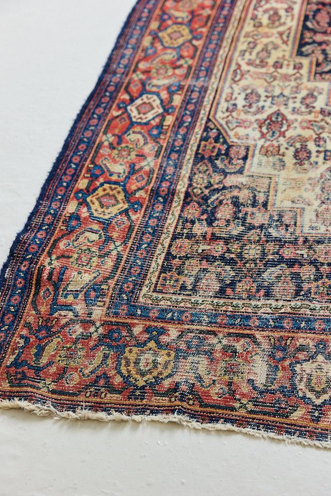Raine is a beautiful antique Senneh rug with an intricate design. Senneh rugs are known for their fine and intricate patterns and distinctive weaving technique. Raine has a central motif surrounded by an intricate pattern and a pleasing colour palette of blue, red and taupe.