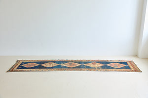 Seraphine is a beautiful antique Oushak runner with a peachy pink repeating pattern on a dark blue ground. Oushak rugs are among the most celebrated of all Turkish weavings, prized for their soft, luminous palettes and characteristically open, large-scale designs