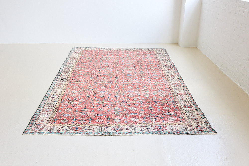 Glenda is a vintage wool rug handwoven in Turkey approximately 80 years ago. The warm terracotta field and is decorated with an all floral scrolls pattern framed by a contrasting taupe boarder.
