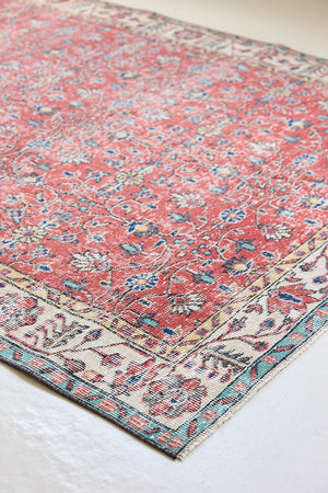 Glenda is a vintage wool rug handwoven in Turkey approximately 80 years ago. The warm terracotta field and is decorated with an all floral scrolls pattern framed by a contrasting taupe boarder.