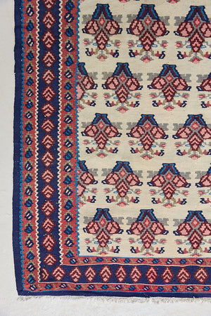 Isolde is a vintage geometric Anatolian kilim rug. Hand-woven on village and nomadic looms in vivid, naturally dyed colours, a tradition stretching back thousands of years. Kilims were woven for the practicalities of daily life and used as floor and wall coverings, storage bags, and prayer mats. Isolde features a pretty pink floral motif across a taupe field with a contrasting dark blue boarder.
