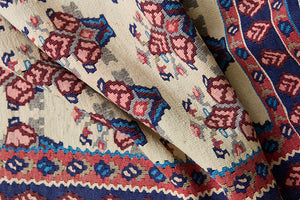 Isolde is a vintage geometric Anatolian kilim rug. Hand-woven on village and nomadic looms in vivid, naturally dyed colours, a tradition stretching back thousands of years. Kilims were woven for the practicalities of daily life and used as floor and wall coverings, storage bags, and prayer mats. Isolde features a pretty pink floral motif across a taupe field with a contrasting dark blue boarder.