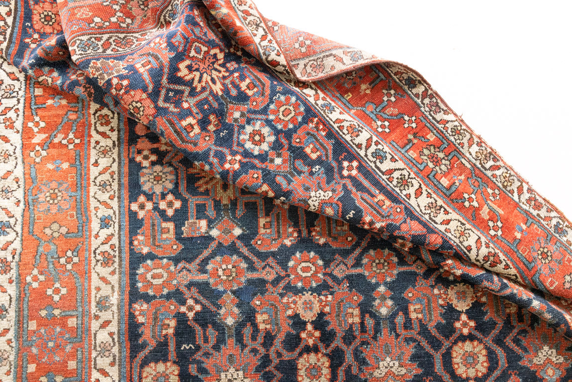 This is a Persian Mahal carpet which are known for decorative designs and repeating floral patterns. This Vintage hand woven rug features a midnight navy ground complimented by a rich red border.