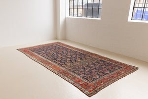 This is a Persian Mahal carpet which are known for decorative designs and repeating floral patterns. This Vintage hand woven rug features a midnight navy ground complimented by a rich red border.