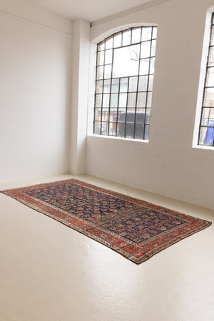 This is a Persian Mahal carpet which are known for decorative designs and repeating floral patterns. This Vintage hand woven rug features a midnight navy ground complimented by a rich red border.