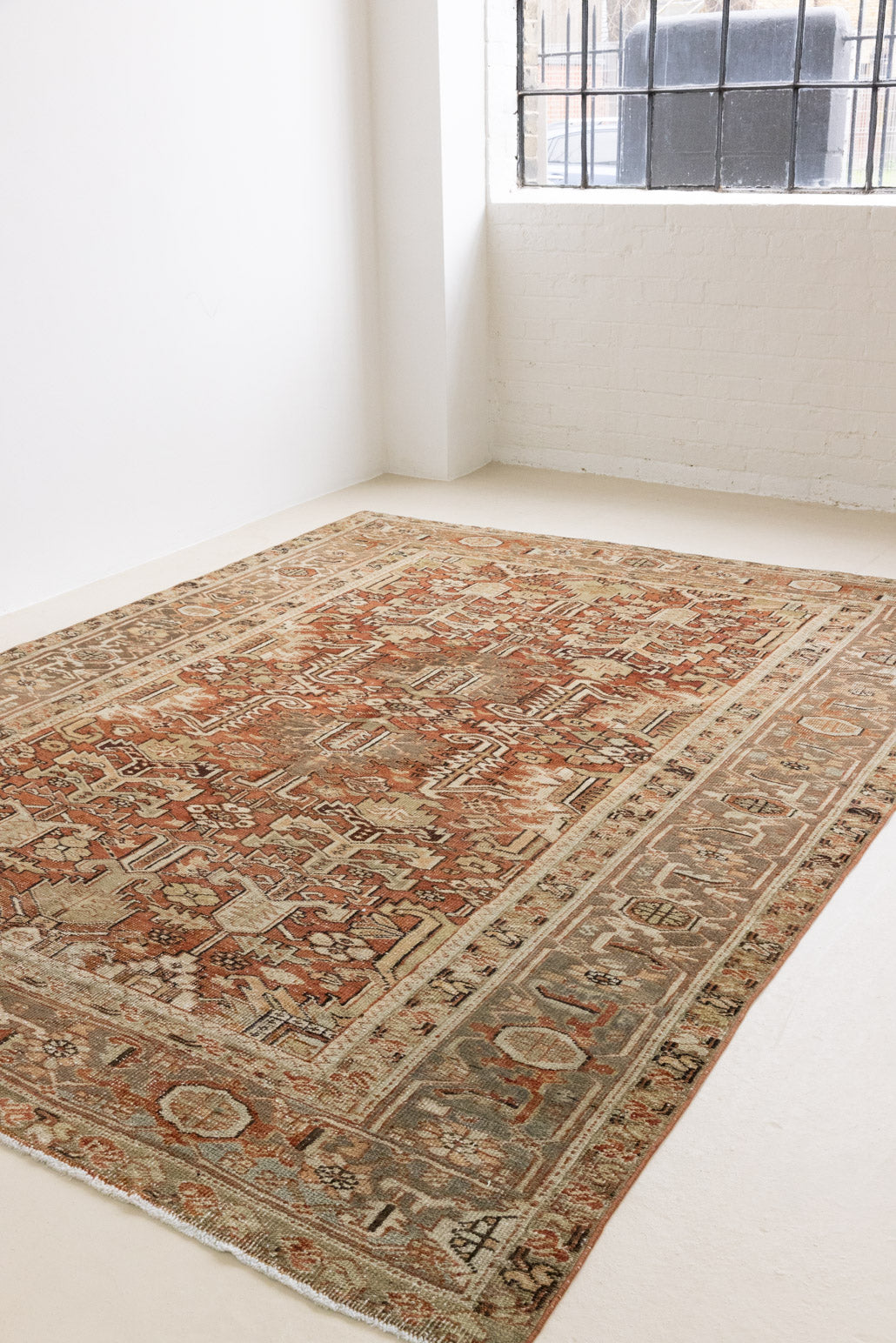 This is a antique Persian Heriz rug that has been over-dyed to gently fade its original colours, giving a more neutral palette. Persia has the most desirable rugs and carpets with stunning designs such as this carpet. Now available at Ourika London.
