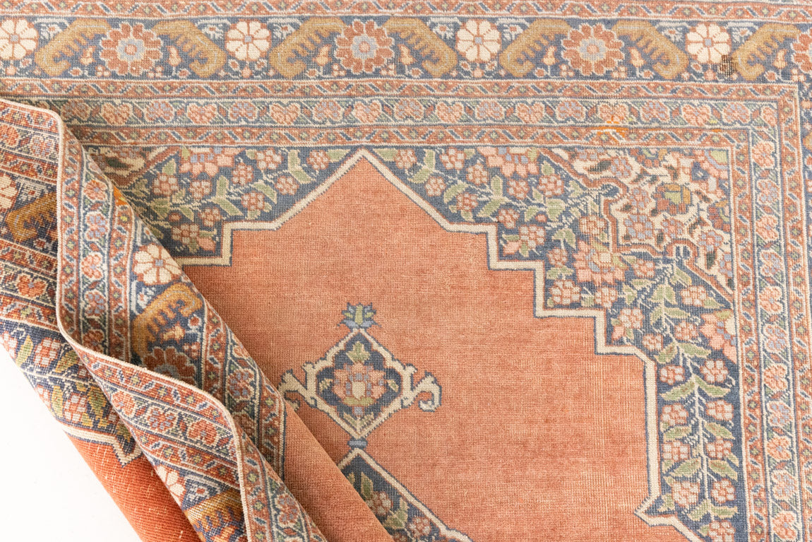 Selma is a beautiful antique Persian Tabriz rug with a soft yet bold coral colour palette and a stunning abrash and patina with a lovely central medallion within the carpet.