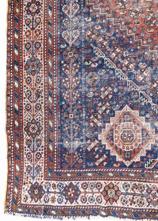 A Qashqai carpet. Sydney features a striking central diamond medallion, a classic motif in Qashqai weaving, framed by a repeating floral, boteh and gul pattern.
