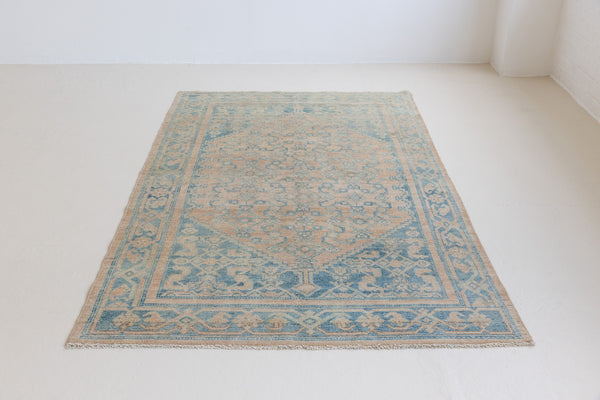 Handwoven antique Persian carpet with a faded pink ground and an angular geometric design in blue