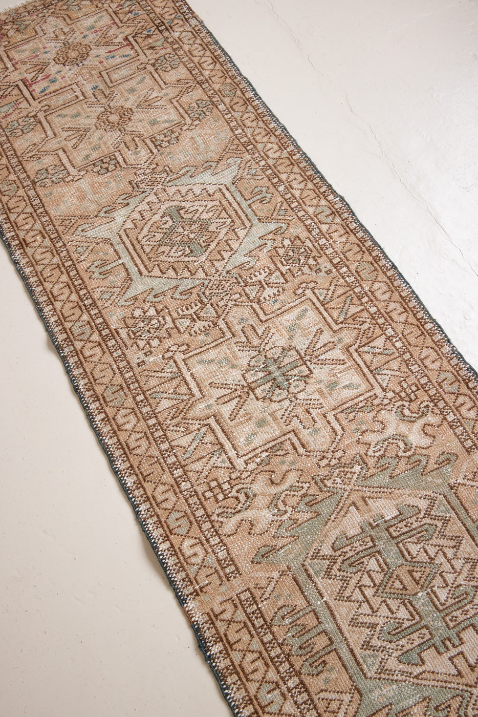 Bonnie is an vintage Persian Heriz runner rug which has been antique washed using a special technique to gently fade its original colours, creating a stunning muted palette. Heriz rugs are some of the most sought after Persian carpets and this one features a classic Heriz design in gorgeous soft blue, taupe and cream tones. 