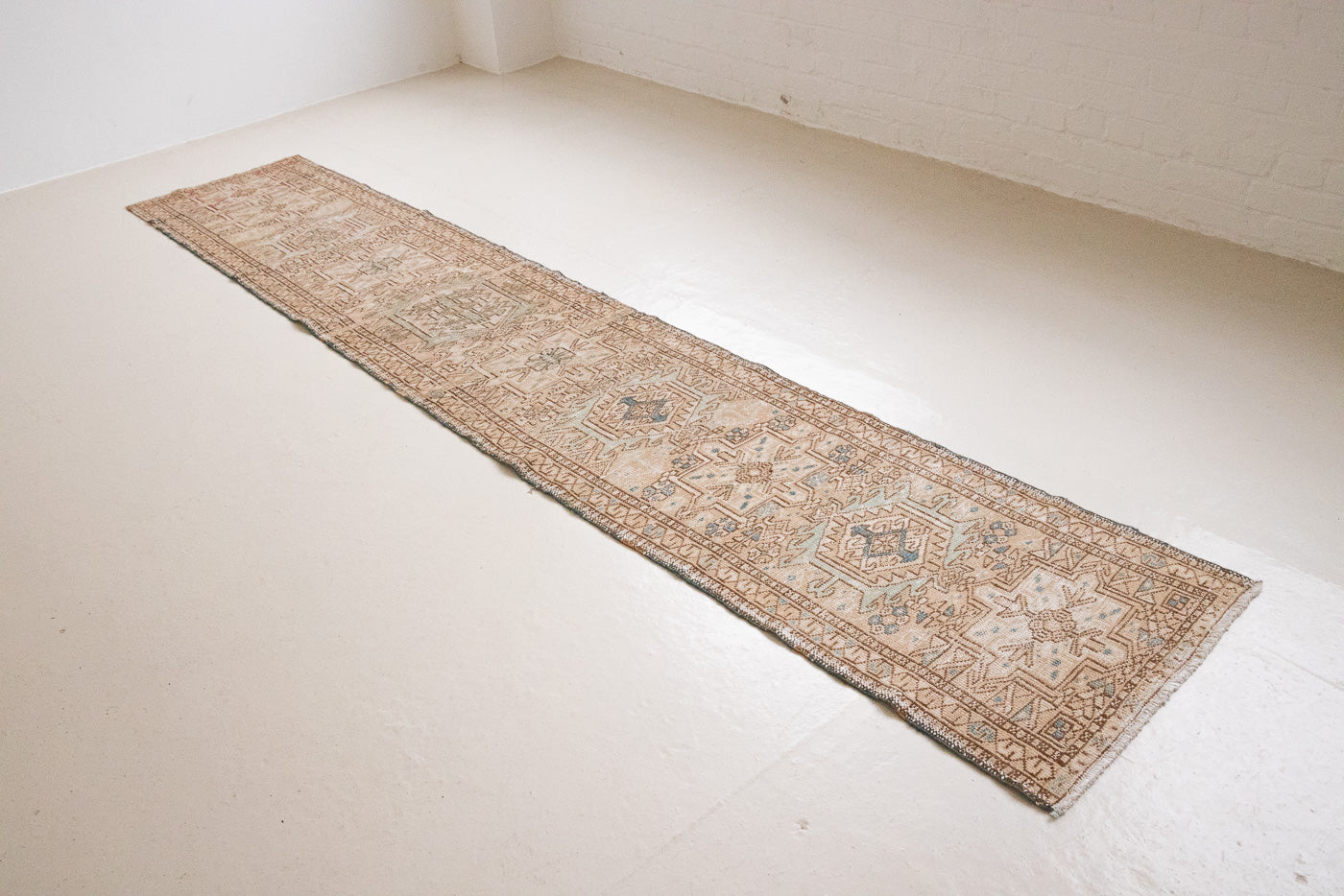 Bonnie is an vintage Persian Heriz runner rug which has been antique washed using a special technique to gently fade its original colours, creating a stunning muted palette. Heriz rugs are some of the most sought after Persian carpets and this one features a classic Heriz design in gorgeous soft blue, taupe and cream tones. 