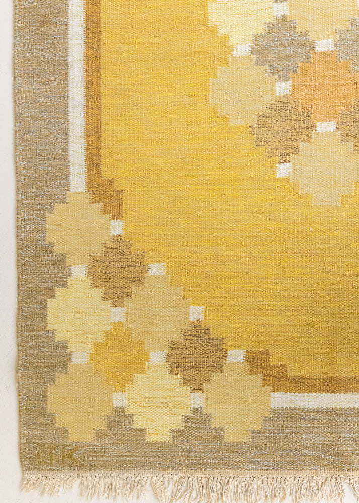 This is an original vintage Swedish flat weave carpet signed by the renowned textile designer Karin Jonsson. This rug features a palette of rich ochre yellow and a beautiful geometric design. 