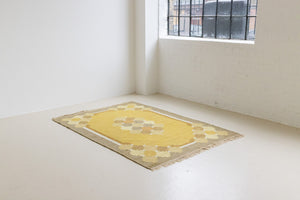 This is an original vintage Swedish flat weave carpet signed by the renowned textile designer Karin Jonsson. This rug features a palette of rich ochre yellow and a beautiful geometric design. 