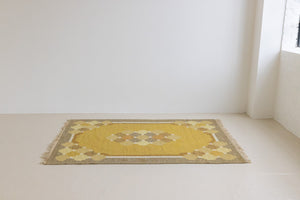 This is an original vintage Swedish flat weave carpet signed by the renowned textile designer Karin Jonsson. This rug features a palette of rich ochre yellow and a beautiful geometric design. 