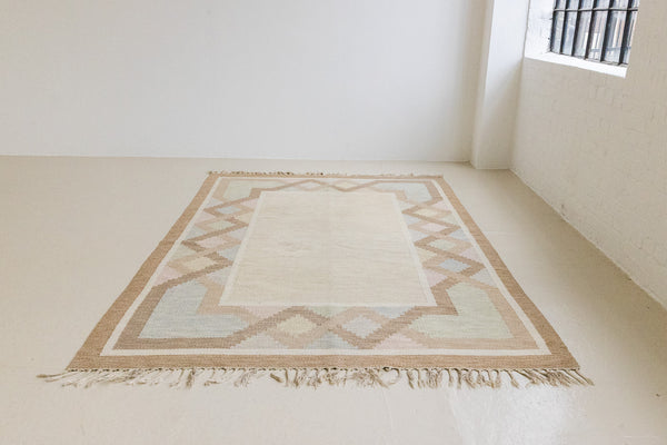 This is an original Swedish röllakan rug handwoven by the mid-century textile designer Anna Johanna Angström. Featuring a geometric patterned rug with pastel colors on a neutral background