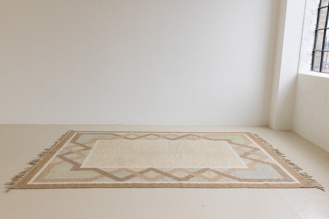 This is an original Swedish röllakan rug handwoven by the mid-century textile designer Anna Johanna Angström. Featuring a geometric patterned rug with pastel colors on a neutral background
