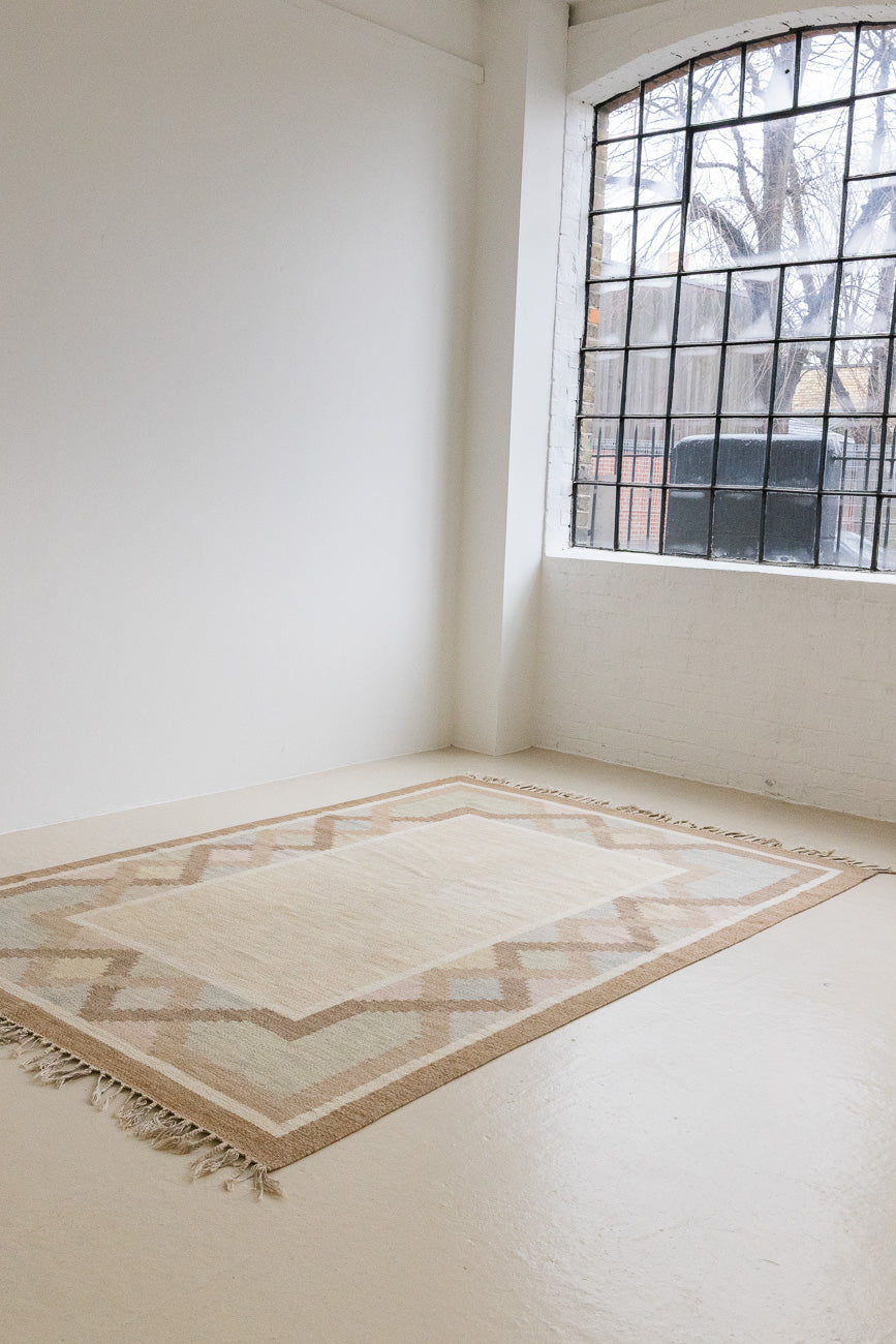 This is an original Swedish röllakan rug handwoven by the mid-century textile designer Anna Johanna Angström. Featuring a geometric patterned rug with pastel colors on a neutral background