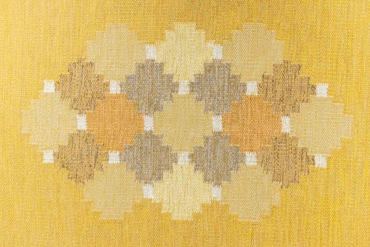 This is an original vintage Swedish flat weave carpet signed by the renowned textile designer Karin Jonsson. This rug features a palette of rich ochre yellow and a beautiful geometric design. 