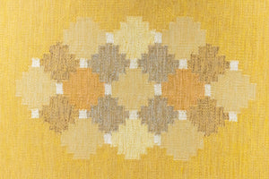 This is an original vintage Swedish flat weave carpet signed by the renowned textile designer Karin Jonsson. This rug features a palette of rich ochre yellow and a beautiful geometric design. 