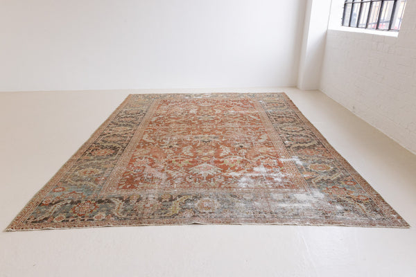 A Heriz carpet. The Heriz is one of the most sought after and recognisable Persian designs, known for vibrant colours and bold geometric patterns. The Penelope rug features an intricate, ubiquitous all-over floral and palmette motifs with a muted rust ground and blue toned boarder.