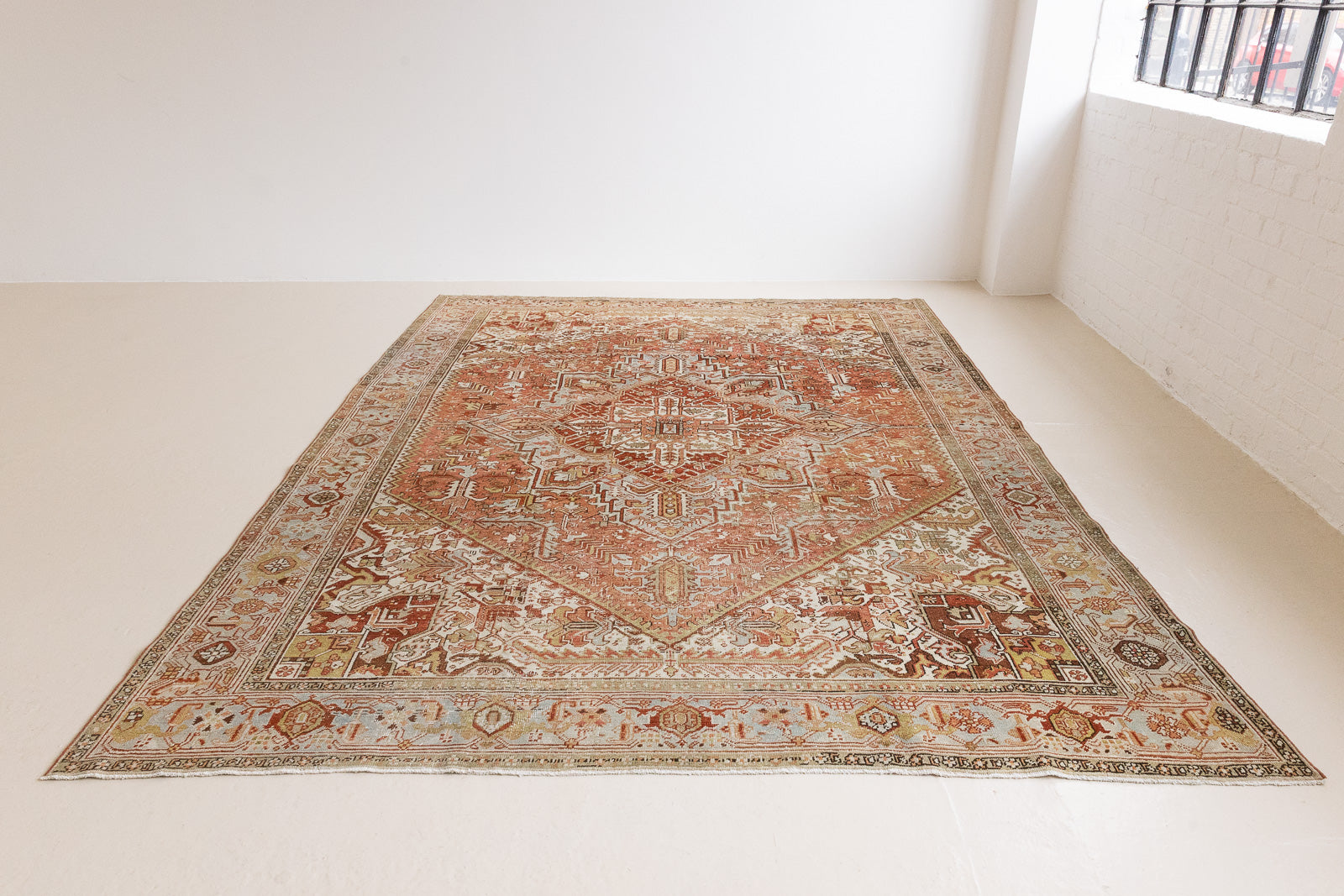Lainey showcases a classic Heriz composition, centred around a striking medallion set against a soft rust-coloured field, complemented by a light khaki-toned border. Traditional palmette and floral motifs are interpreted through bold, geometric patterns.