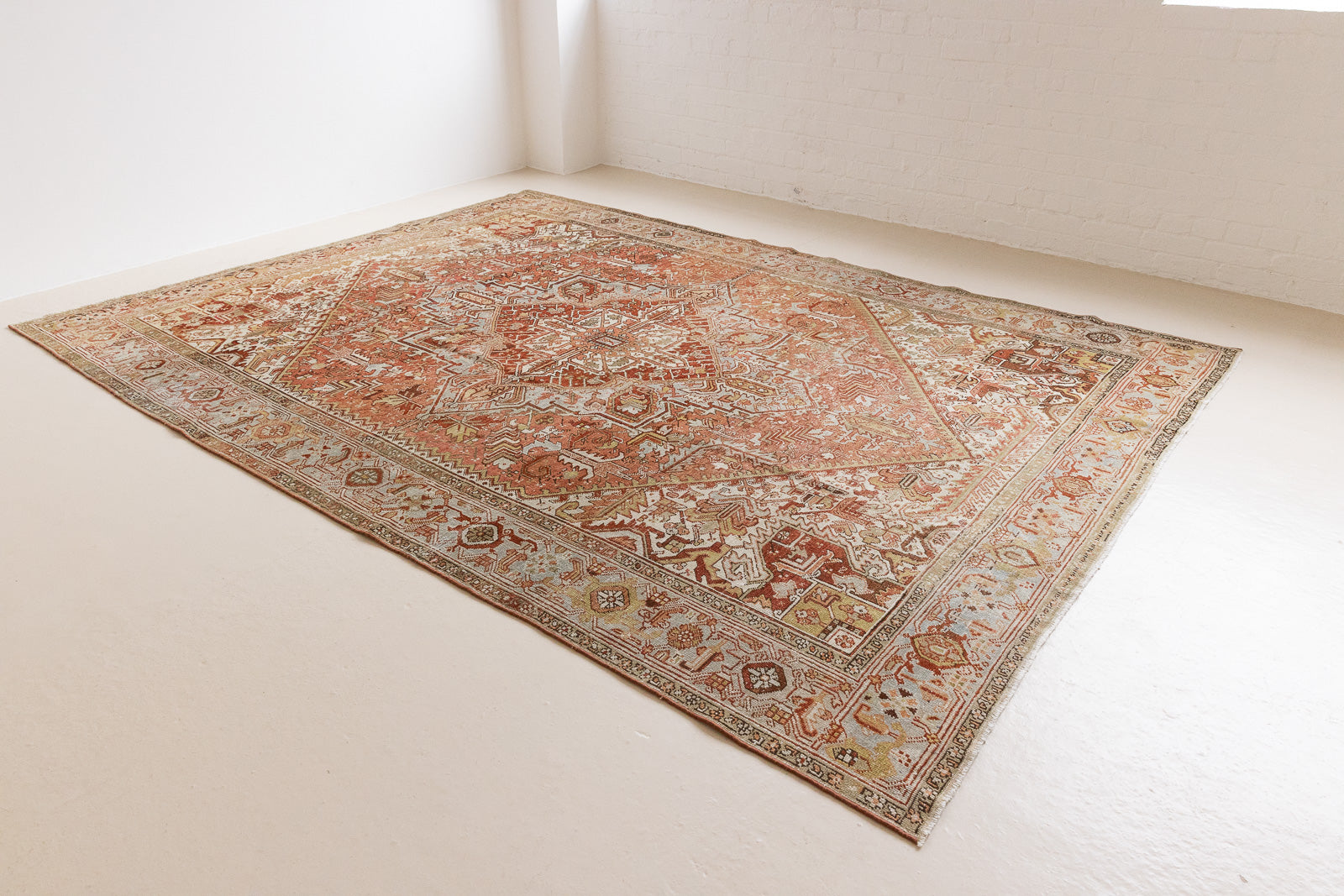Lainey showcases a classic Heriz composition, centred around a striking medallion set against a soft rust-coloured field, complemented by a light khaki-toned border. Traditional palmette and floral motifs are interpreted through bold, geometric patterns.