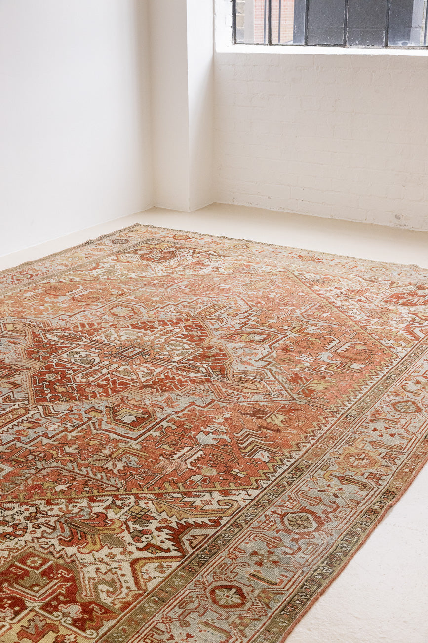 Lainey showcases a classic Heriz composition, centred around a striking medallion set against a soft rust-coloured field, complemented by a light khaki-toned border. Traditional palmette and floral motifs are interpreted through bold, geometric patterns.