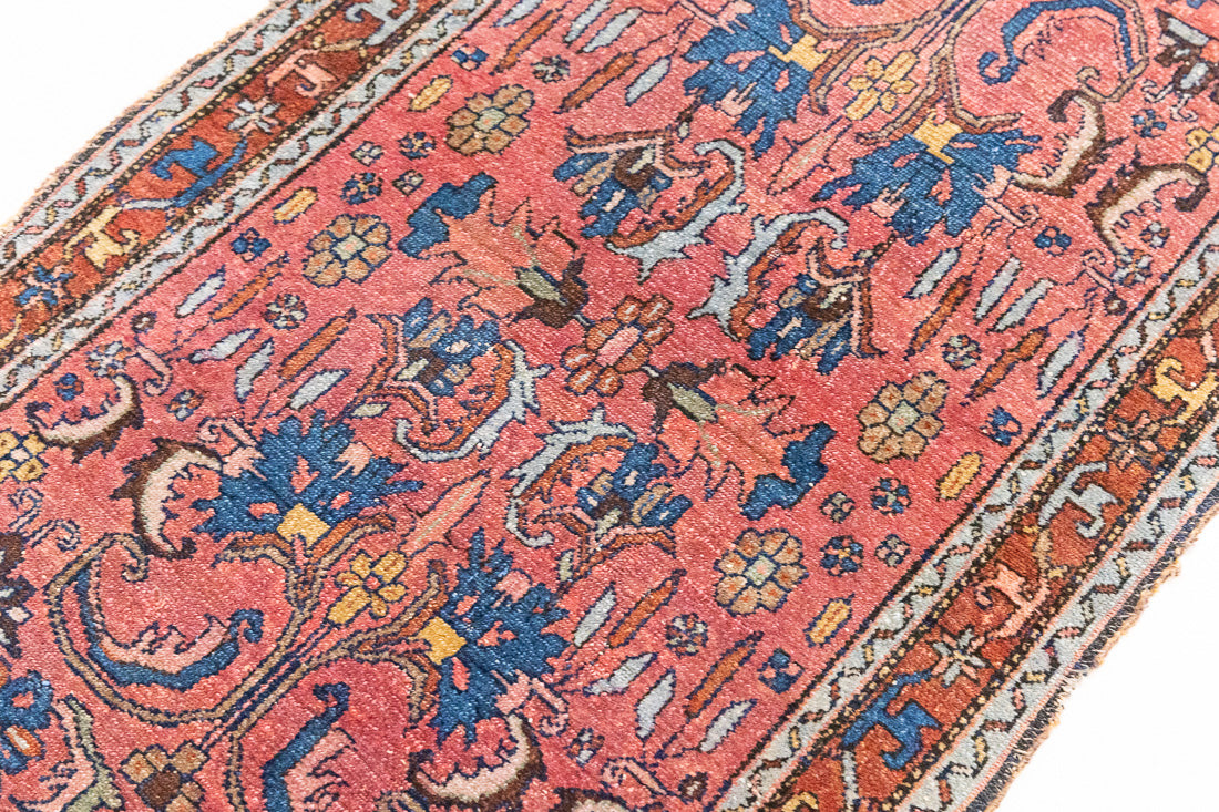 This Vintage rug was handwoven in a small village in Western Persia and features floral and geometric patterns and hints of pink and blue.