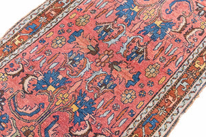 This Vintage rug was handwoven in a small village in Western Persia and features floral and geometric patterns and hints of pink and blue.