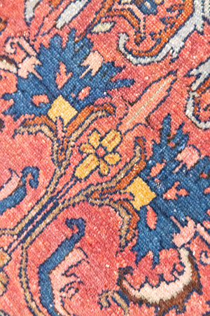 This Vintage rug was handwoven in a small village in Western Persia and features floral and geometric patterns and hints of pink and blue.