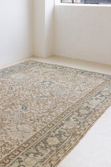 The Portia rug features an intricate all over Heriz design comprised of floral and palmette motifs set against a taupe ground and muted blue toned boarder. A beautiful antique carpet.