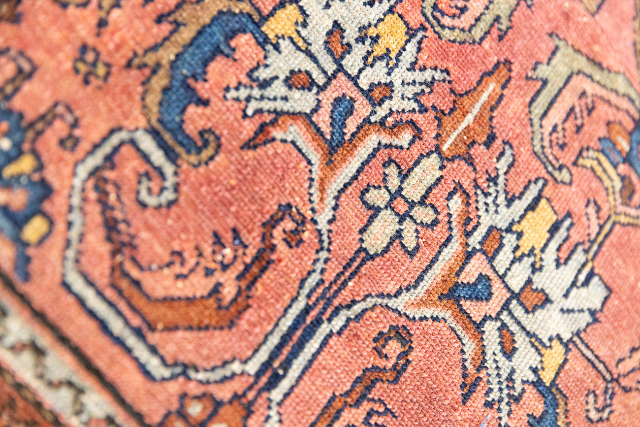This Vintage rug was handwoven in a small village in Western Persia and features floral and geometric patterns and hints of pink and blue.