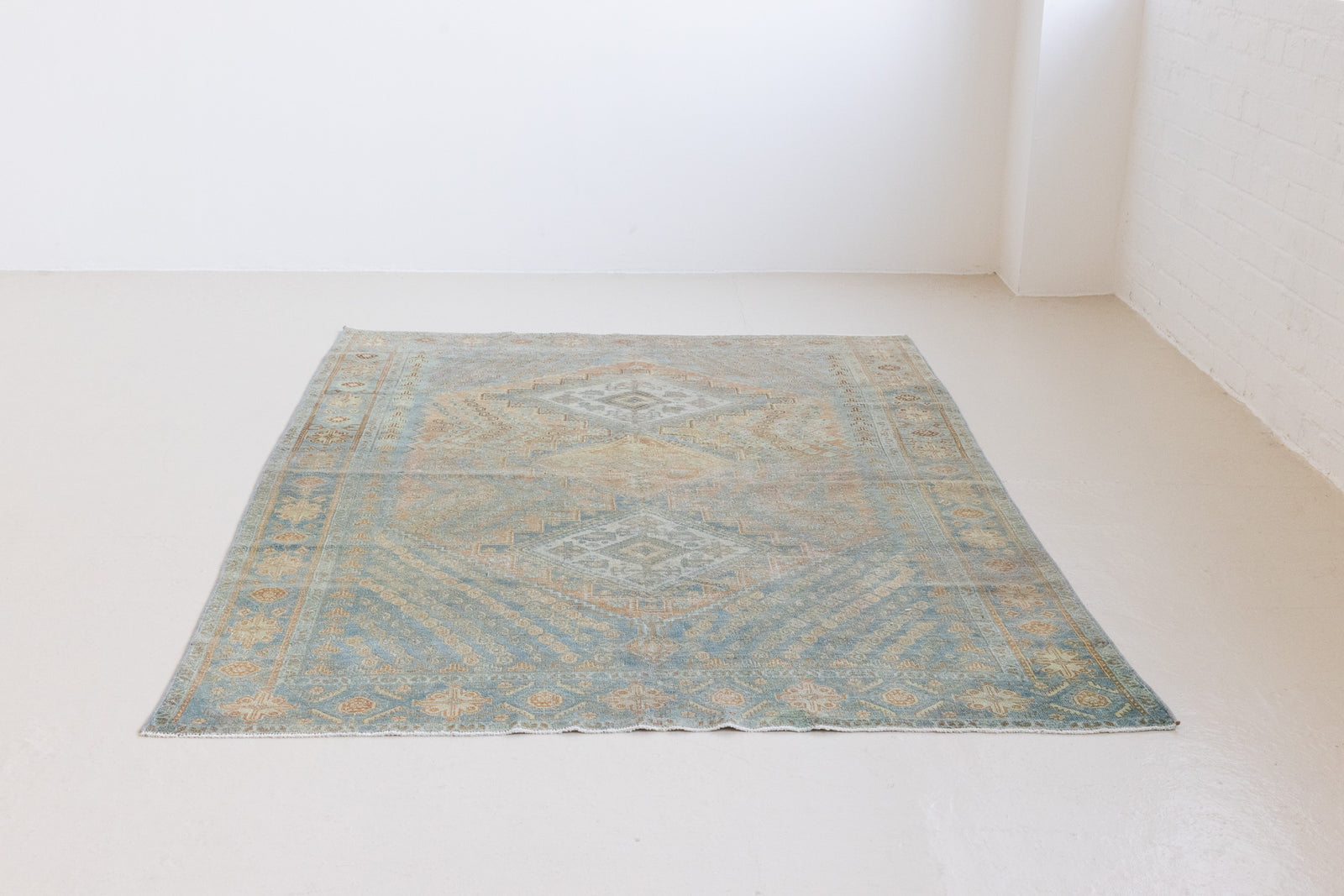 This is an Vintage Qashqai nomadic rug featuring a soft natural blue and orange with beautifully intricate designs within this handwoven carpet, a repeating boteh pattern frames the central diamond motifs.