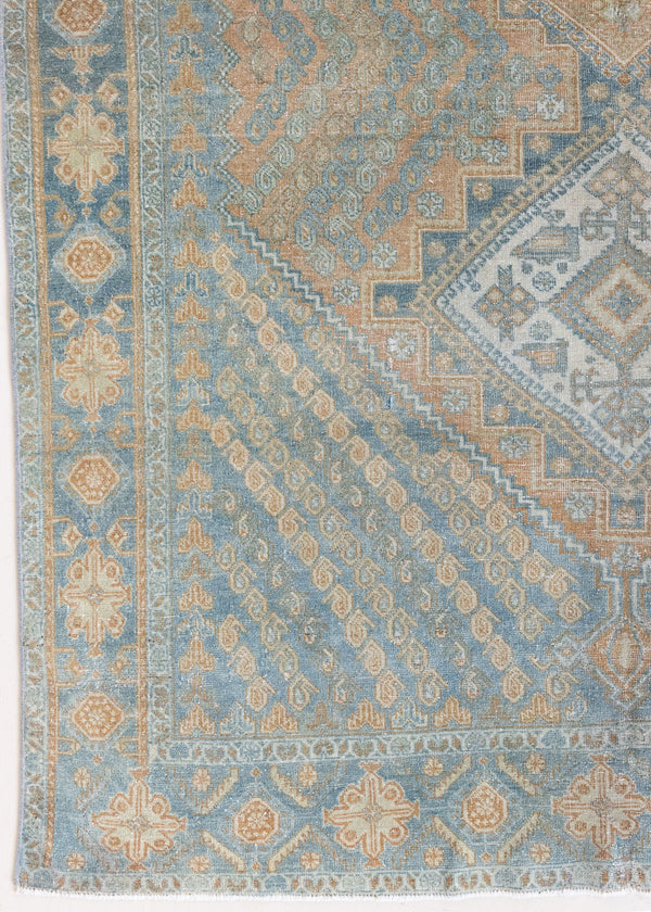 This is an Vintage Qashqai nomadic rug featuring a soft natural blue and orange with beautifully intricate designs within this handwoven carpet, a repeating boteh pattern frames the central diamond motifs.