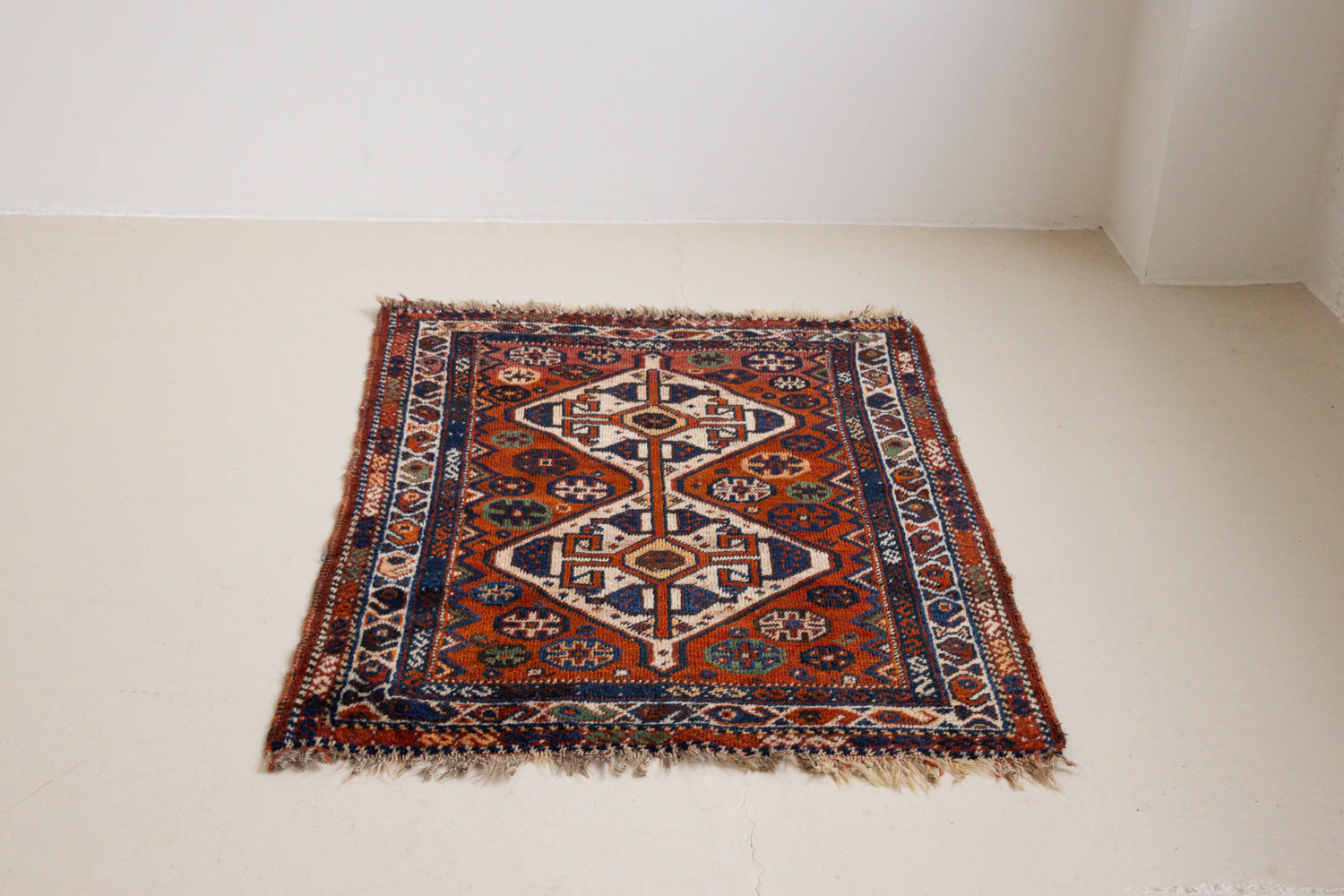 Gigi features a striking central diamond medallion, a classic motif in Qashqai weaving, framed by a repeating floral and gul pattern and a boteh patterned boarder.