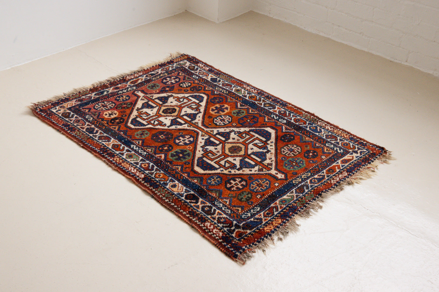 Gigi features a striking central diamond medallion, a classic motif in Qashqai weaving, framed by a repeating floral and gul pattern and a boteh patterned boarder.